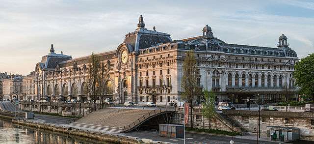 Large building about 1-2 blocks in size with arches, clocks and stairs that lead to the river in Paris